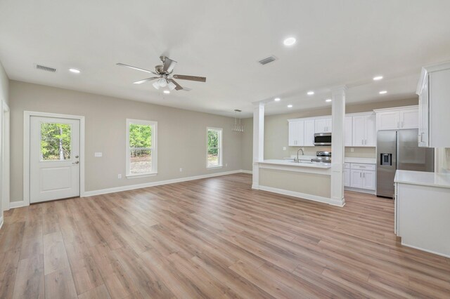 unfurnished living room featuring ceiling fan, decorative columns, sink, and light hardwood / wood-style floors