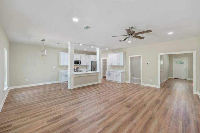 unfurnished living room with ceiling fan, light wood-type flooring, and sink