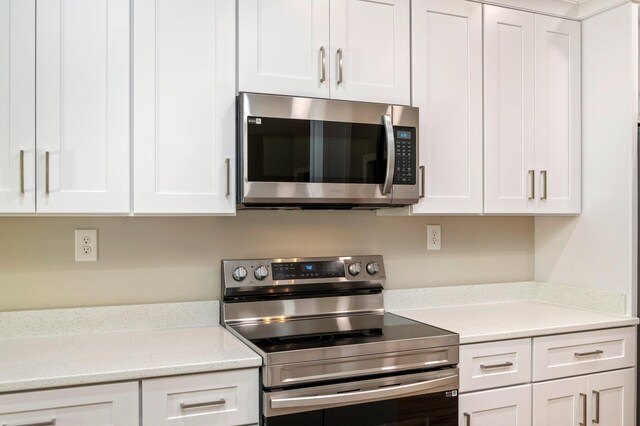 kitchen featuring white cabinetry, light stone counters, and stainless steel appliances