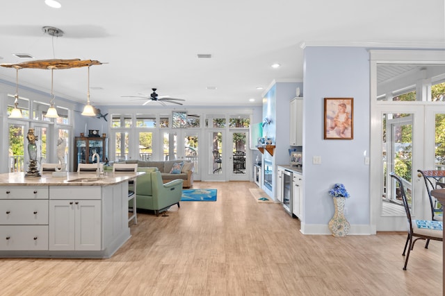 kitchen with sink, light wood-type flooring, plenty of natural light, and beverage cooler