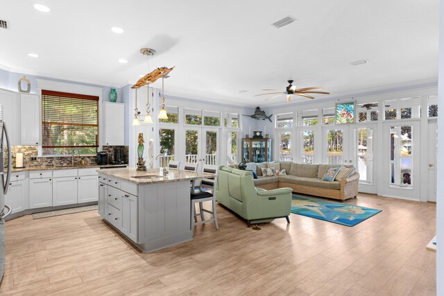 kitchen featuring ceiling fan, light hardwood / wood-style flooring, pendant lighting, white cabinetry, and a center island