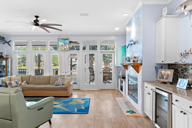 living room with ornamental molding, french doors, wine cooler, light wood-type flooring, and ceiling fan