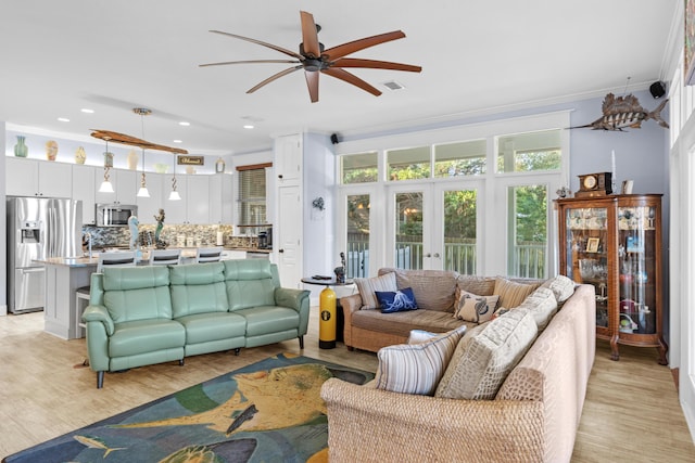 living room featuring ceiling fan, crown molding, and light hardwood / wood-style floors