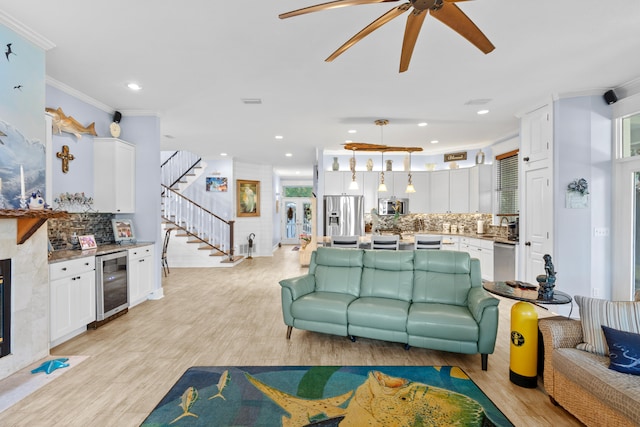 living room with ceiling fan, light hardwood / wood-style floors, wine cooler, and ornamental molding