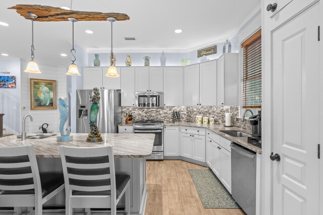 kitchen with decorative backsplash, light stone counters, appliances with stainless steel finishes, and pendant lighting