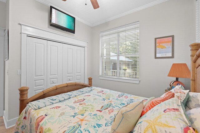 bedroom with ceiling fan, a closet, crown molding, and hardwood / wood-style floors