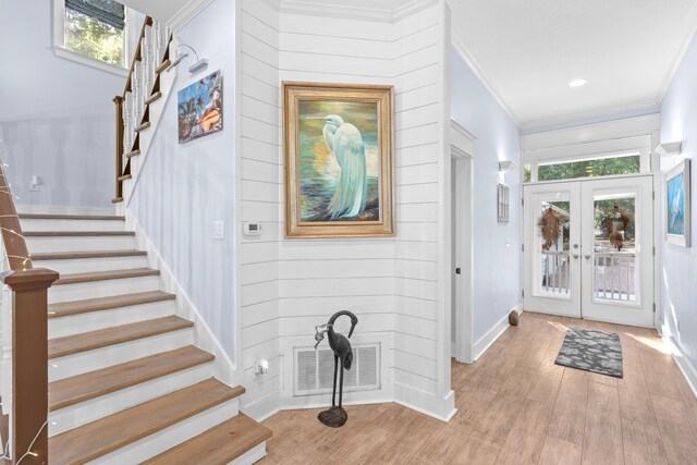 entrance foyer with light hardwood / wood-style flooring, crown molding, and french doors