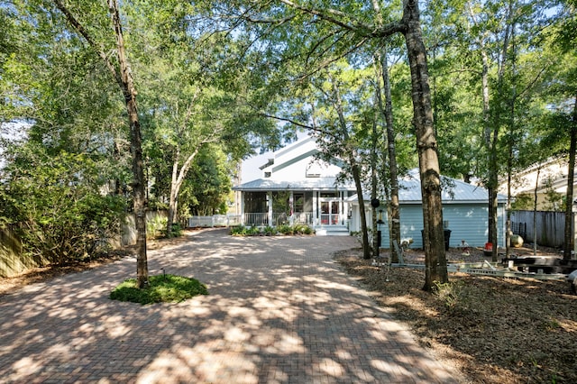 view of front facade with a porch, decorative driveway, and fence