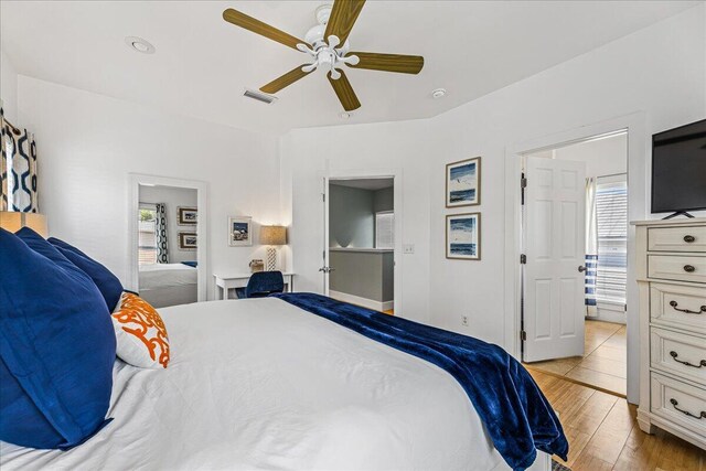 bedroom with ceiling fan, light wood-type flooring, and ensuite bathroom