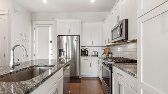 kitchen featuring dark hardwood / wood-style flooring, dark stone counters, sink, and appliances with stainless steel finishes