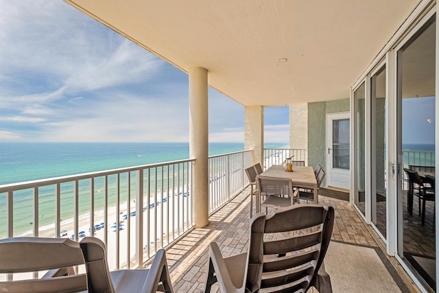 balcony with a water view and a view of the beach