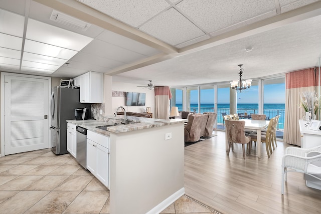 kitchen with pendant lighting, white cabinets, a sink, and open floor plan