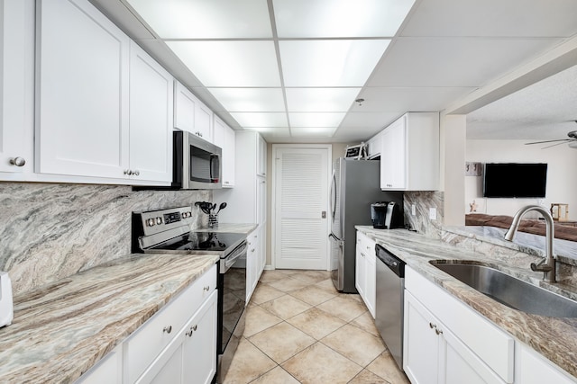 kitchen with stainless steel appliances, white cabinetry, tasteful backsplash, sink, and ceiling fan