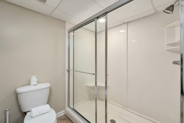 bathroom with a drop ceiling, a shower stall, and toilet