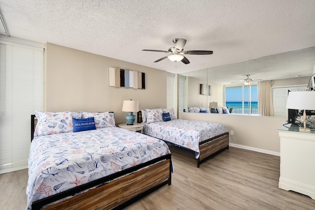 bedroom with ceiling fan, light wood-style flooring, baseboards, and a textured ceiling