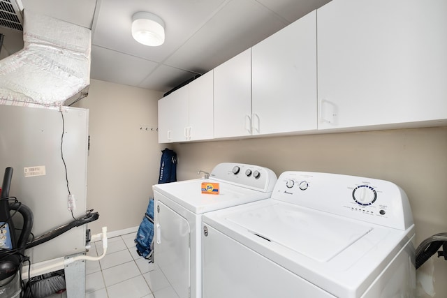 clothes washing area featuring light tile patterned floors, cabinet space, and separate washer and dryer