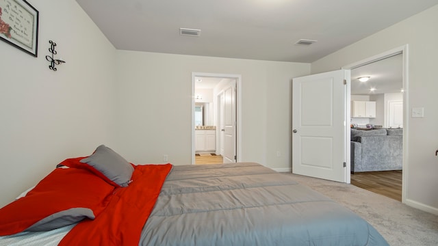 bedroom with connected bathroom and wood-type flooring