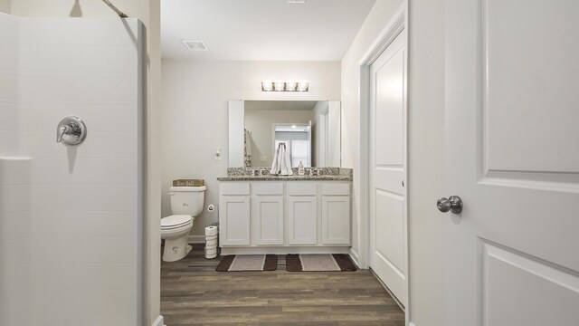 bathroom with toilet, hardwood / wood-style flooring, a shower, and vanity