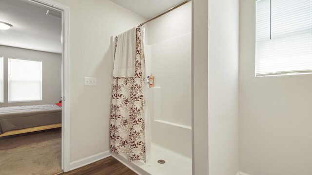 bathroom with curtained shower, hardwood / wood-style floors, and a healthy amount of sunlight