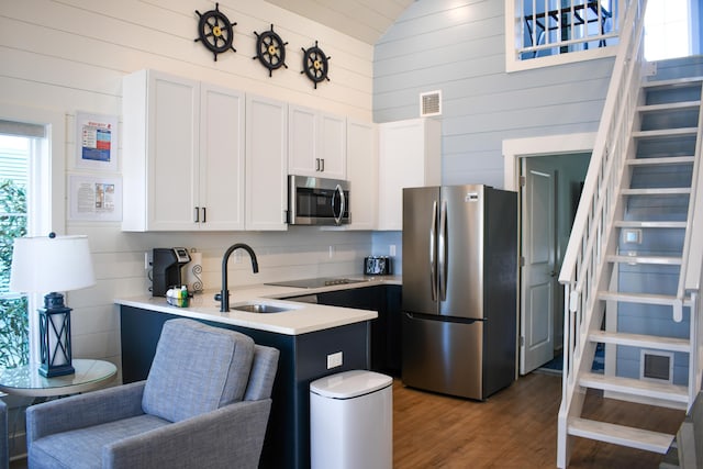 kitchen with appliances with stainless steel finishes, lofted ceiling, white cabinetry, dark hardwood / wood-style flooring, and sink