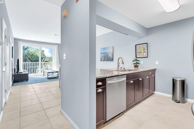 kitchen featuring dark brown cabinetry, light stone counters, stainless steel dishwasher, light tile patterned floors, and sink