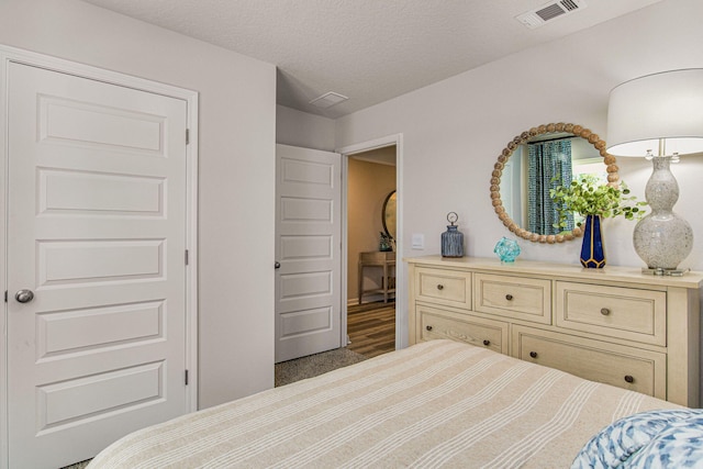 bedroom featuring a textured ceiling and dark carpet