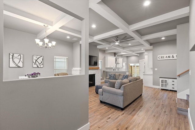 living room featuring light wood-type flooring, coffered ceiling, ceiling fan with notable chandelier, and a wealth of natural light