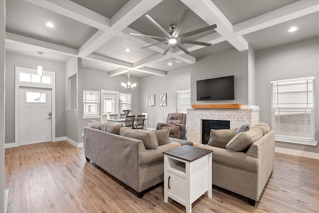 living room featuring coffered ceiling, a fireplace, beamed ceiling, and light hardwood / wood-style flooring