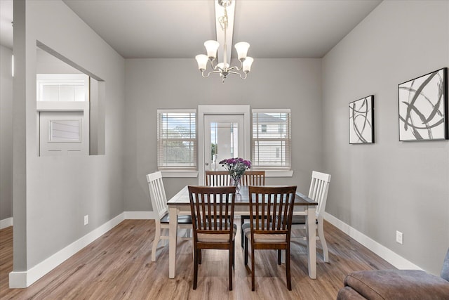 dining space with light wood-type flooring, an inviting chandelier, and baseboards