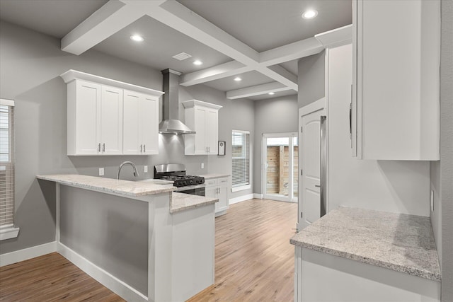 kitchen featuring light wood-type flooring, wall chimney exhaust hood, white cabinetry, and gas stove