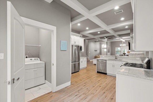 kitchen with washer / clothes dryer, stainless steel appliances, coffered ceiling, and light hardwood / wood-style floors