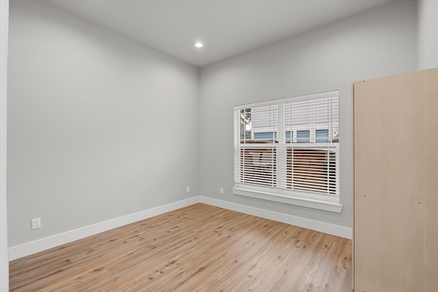 empty room with light wood-type flooring, baseboards, and recessed lighting