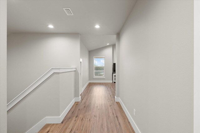 corridor featuring light hardwood / wood-style floors and vaulted ceiling