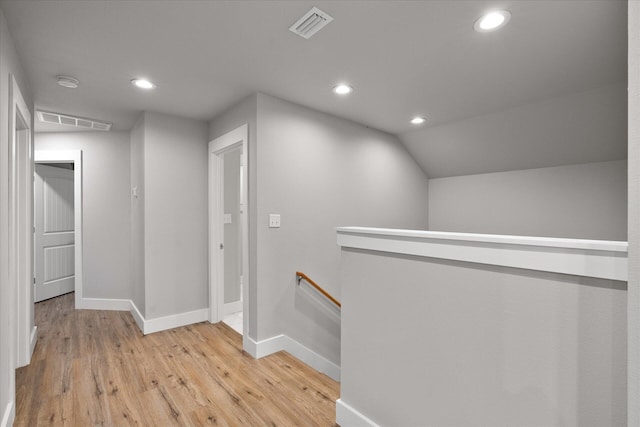 corridor with vaulted ceiling and light wood-type flooring