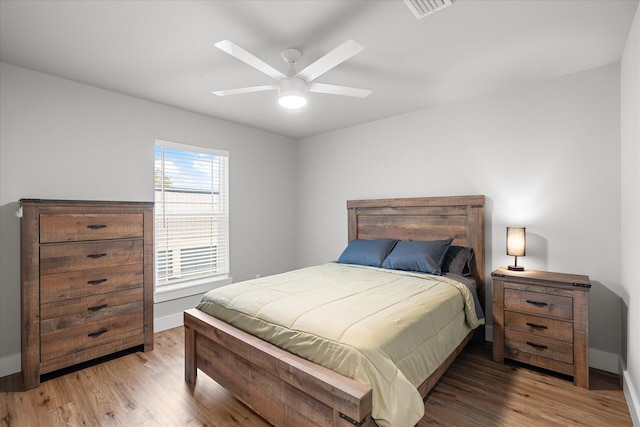 bedroom featuring baseboards, visible vents, ceiling fan, and wood finished floors