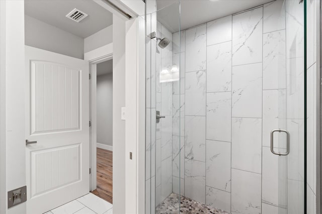 full bathroom featuring a stall shower, baseboards, visible vents, and wood finished floors