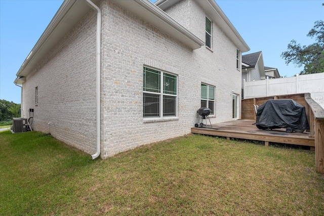 back of property featuring brick siding, a yard, central AC unit, and a wooden deck