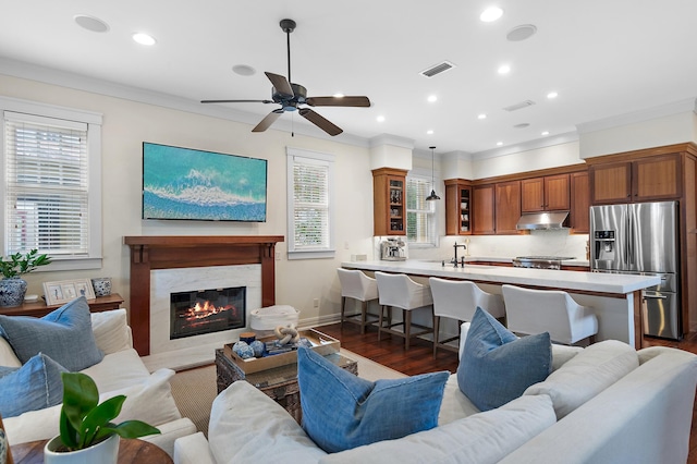 living room featuring a high end fireplace, a wealth of natural light, dark wood-type flooring, and ceiling fan