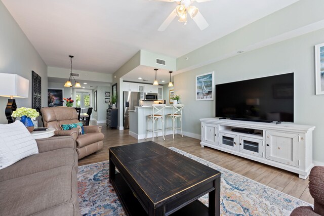 living room featuring ceiling fan and light hardwood / wood-style floors