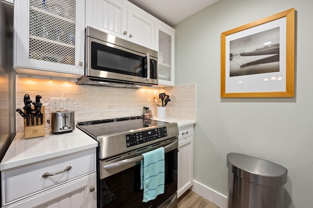 kitchen with light hardwood / wood-style flooring, stainless steel appliances, decorative backsplash, and white cabinetry