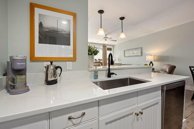 kitchen featuring hanging light fixtures, light hardwood / wood-style floors, white cabinets, stainless steel dishwasher, and sink