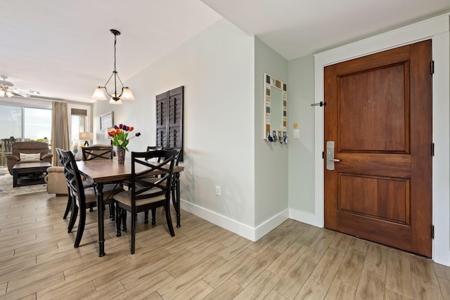 dining space with ceiling fan with notable chandelier and light wood-type flooring