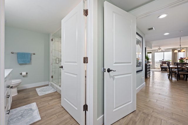 bathroom featuring hardwood / wood-style floors, vanity, a shower with shower door, and toilet