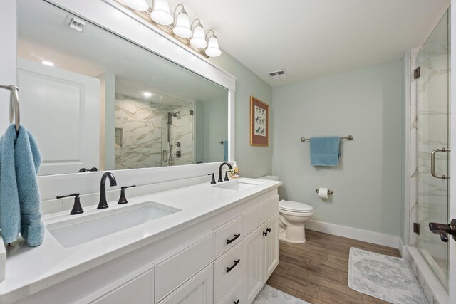 bathroom featuring wood-type flooring, vanity, toilet, and a shower with door