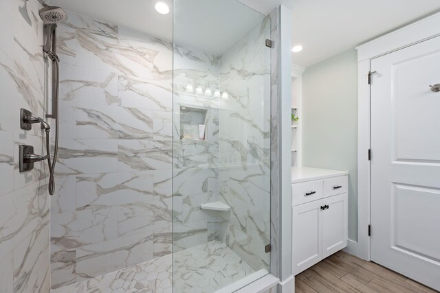 bathroom with wood-type flooring, vanity, and tiled shower