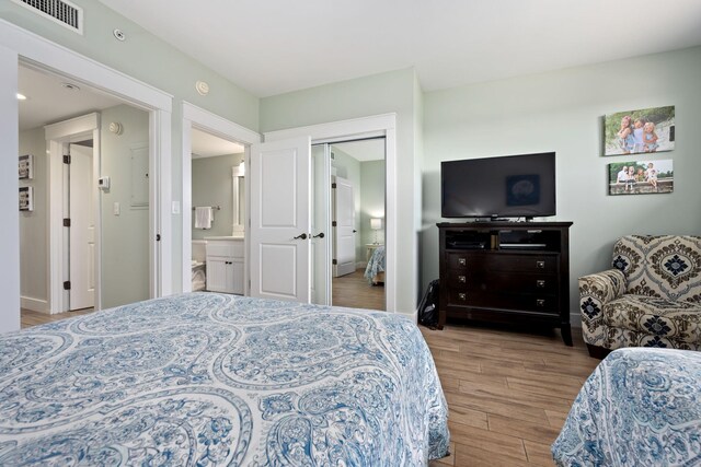 bedroom with a closet, ensuite bath, and light hardwood / wood-style floors