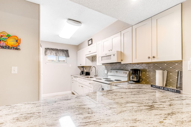 kitchen with white cabinetry, light stone counters, backsplash, and white appliances