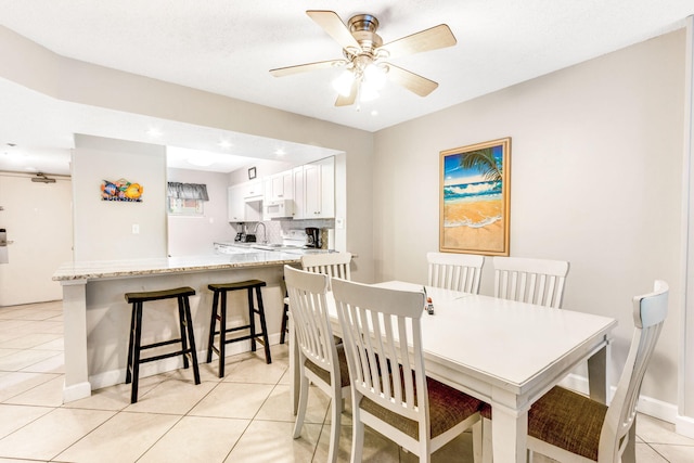 dining room with sink, light tile patterned floors, and ceiling fan