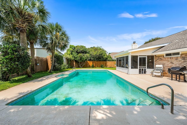 view of swimming pool featuring a sunroom and a patio area