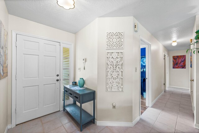 entrance foyer with a textured ceiling and light tile patterned flooring